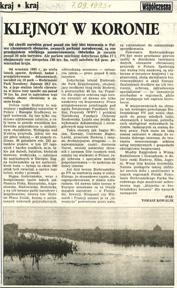 Skan artykułu "Klejnot w koronie" o powołaniu Biebrzańskiego PN. Tekst i jedno zdjęcie rzeki ze stogami siana w tle.