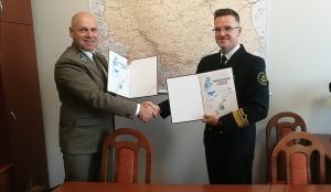 Pan dyrektor BbPN i i Pan dyrektor Delegatury w Giżycku UŻŚ w trakcie uścisku dłoni i pokazywania podpisanych porozumień.