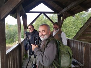 Kilka osób stojących na wieży widokowej i uśmiechających się do fotografującego.