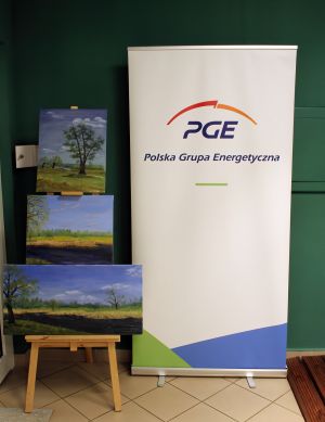 Obraz na stojaku pod ścianą, a obok niego rollbaner z logo Fundacji PGE