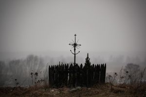 Śródpolna metalowa, stara kapliczka w formie krzyża i ogrodzenia.