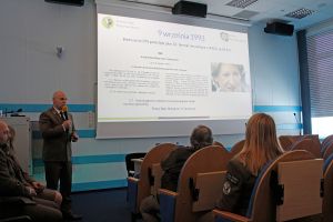 Dyrektor Parku przemawiający do mikrofonu na sali konferencyjnej. W tle ekran prezentacji.